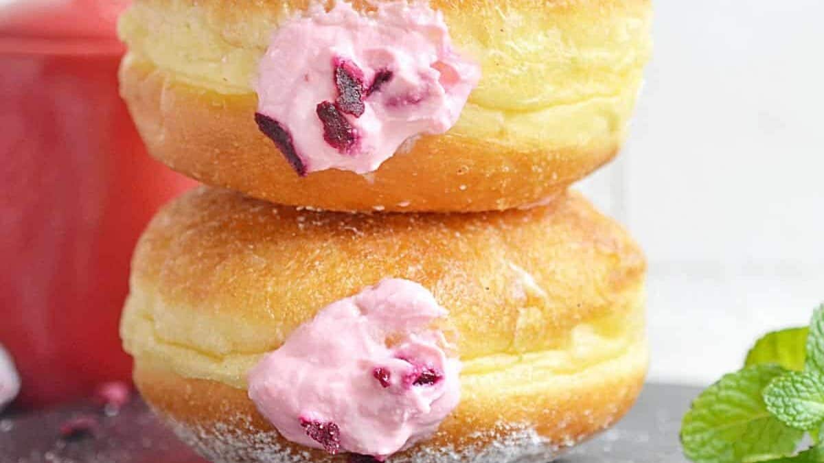 Three donuts stacked on top of each other with pink icing.