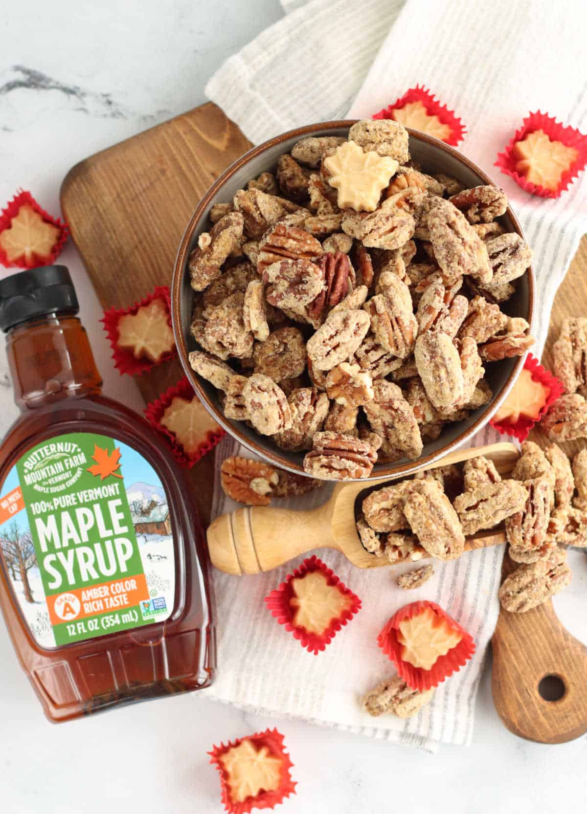 Maple syrup and pecans on a cutting board.