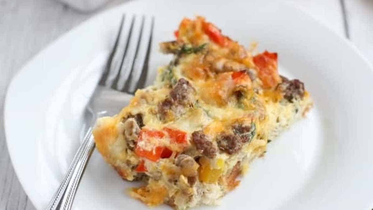 Breakfast casserole with sausage and peppers on a white plate.