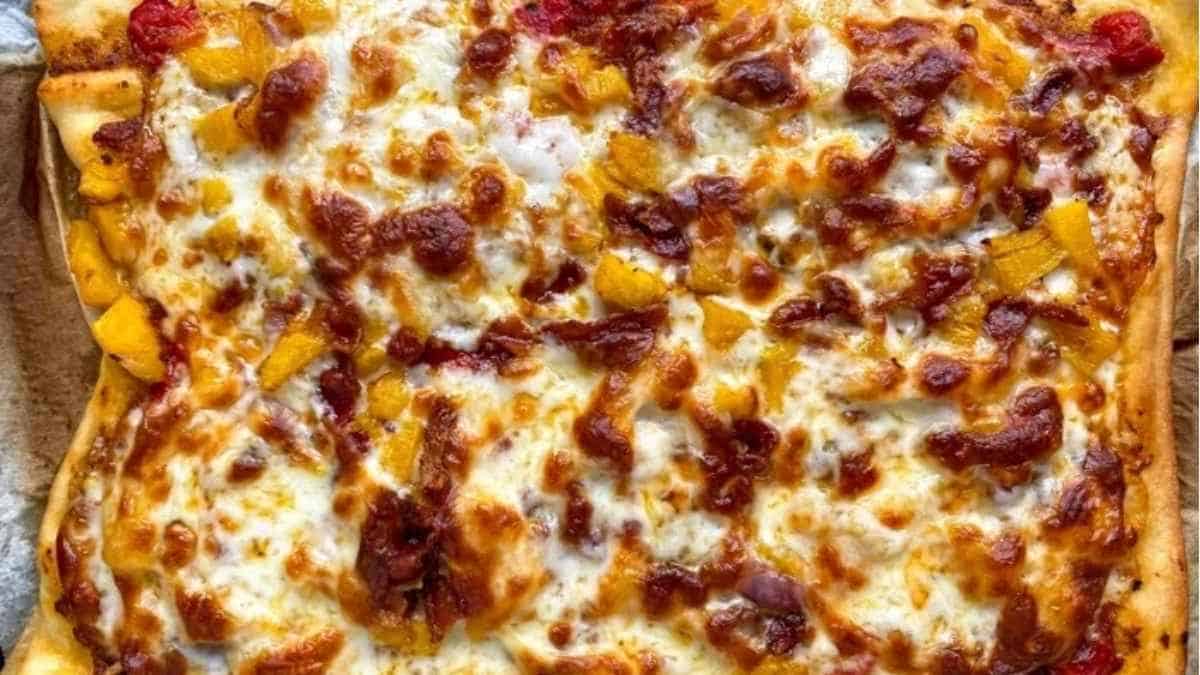 یک پیتزا با پنیر و گوجه فرنگی روی آن.