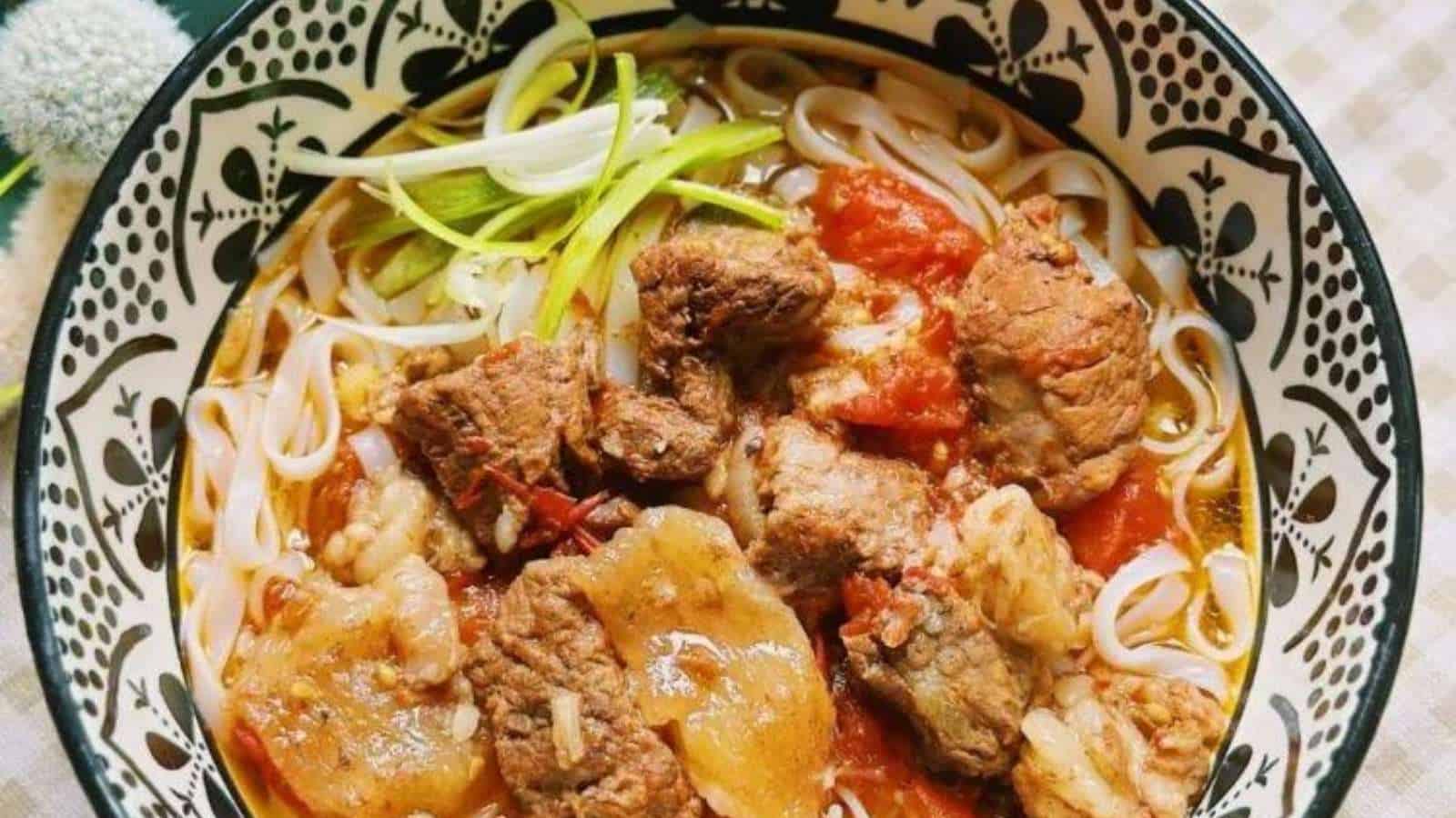 A bowl of noodles with meat and vegetables in it.