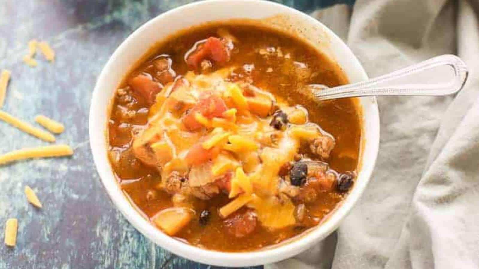 A bowl of chili in a white bowl with a spoon.