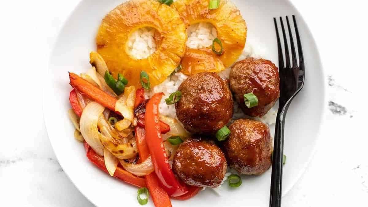 A white plate with meatballs and vegetables on it.