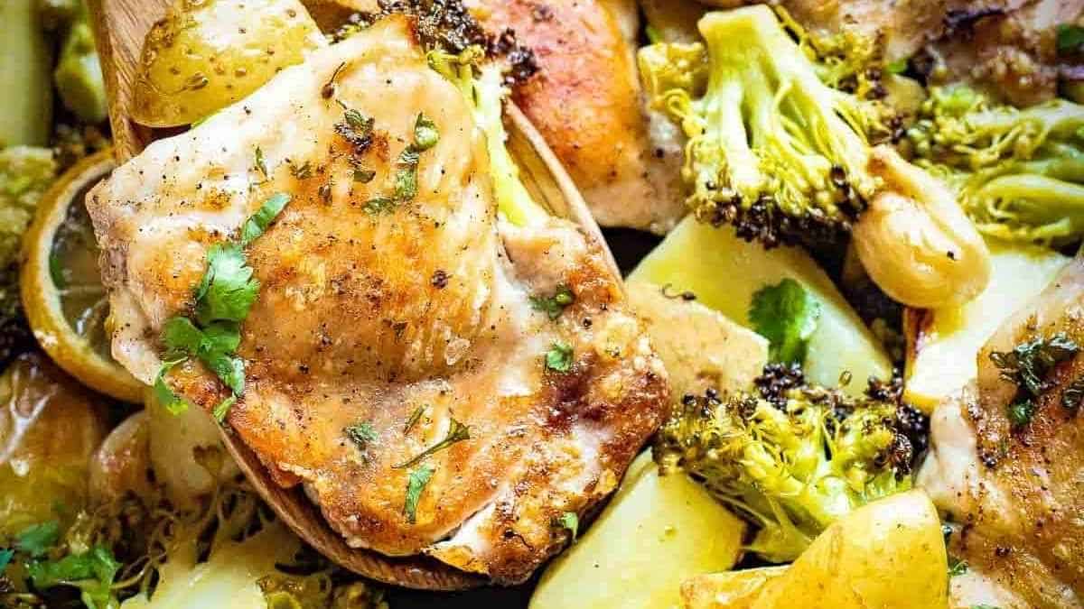 A dish of chicken, potatoes and broccoli on a wooden spoon.