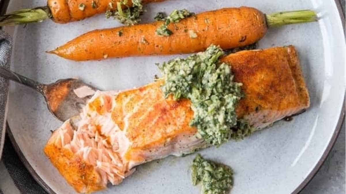 Salmon with pesto sauce and carrots on a plate.