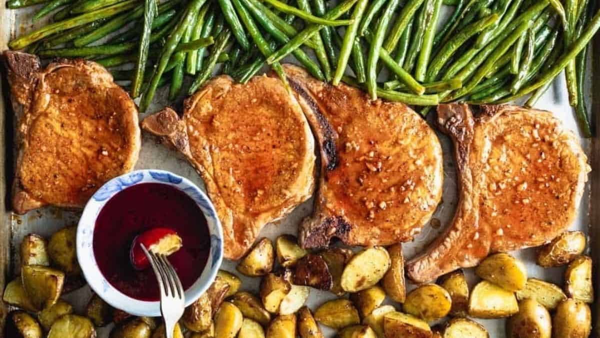 Pork chops and green beans on a baking sheet.