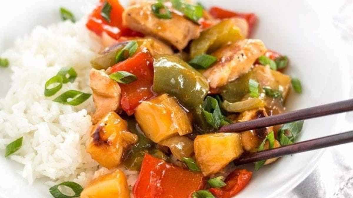 Chicken stir fry with peppers and rice in a white bowl.