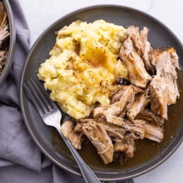 Pulled pork on a plate with mashed potatoes.