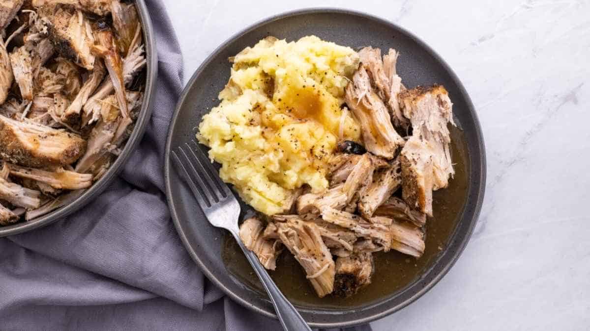Pulled pork on a plate with mashed potatoes.