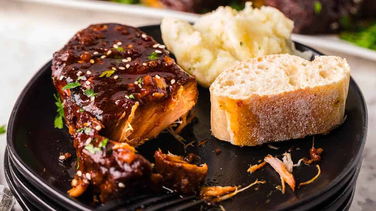 Bbq ribs on a plate with mashed potatoes and bread.