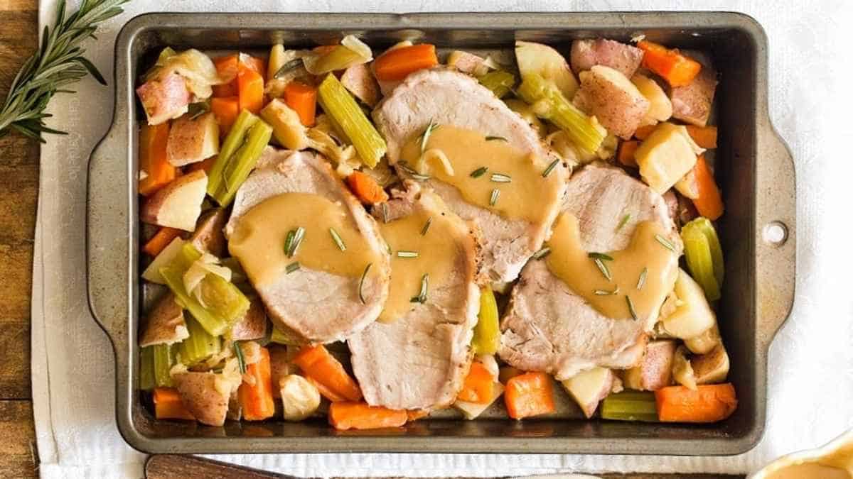 Roasted turkey with gravy and vegetables in a baking pan.