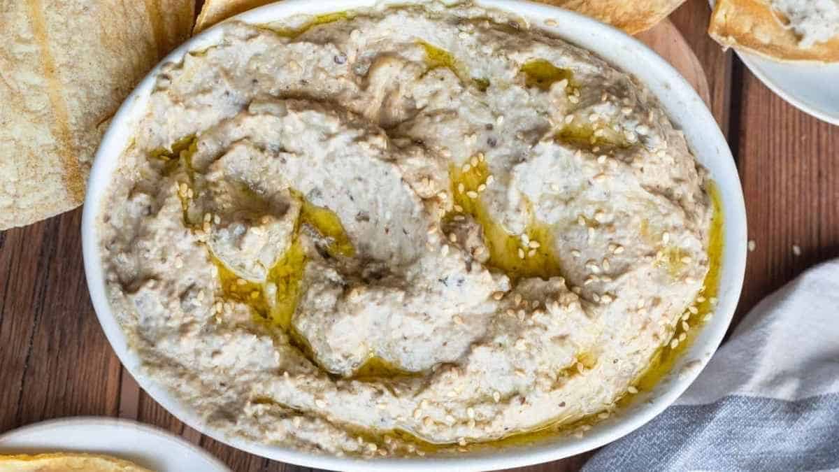 A bowl of hummus with pita bread on a wooden table.