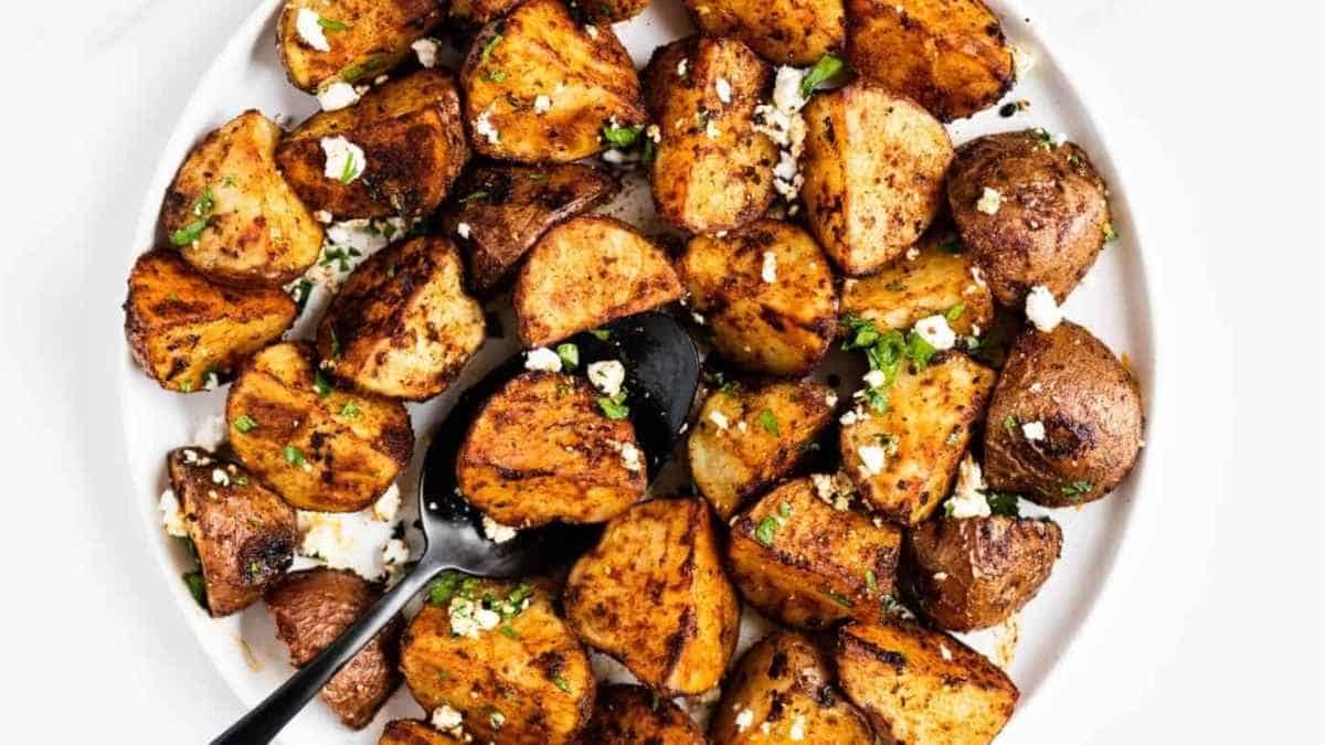 Roasted potatoes on a white plate with a black fork.