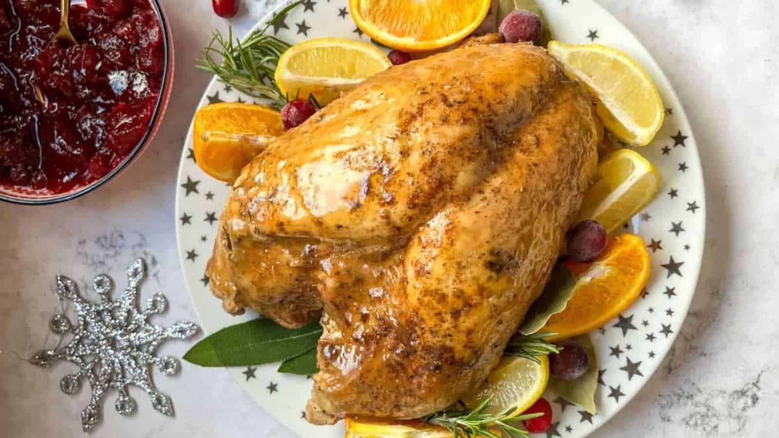 A roast turkey on a plate with oranges and cranberry sauce.