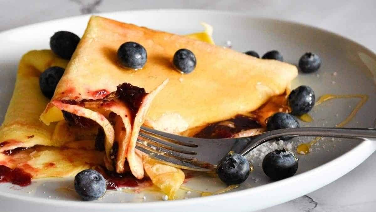Crepes with blueberries and syrup on a plate.