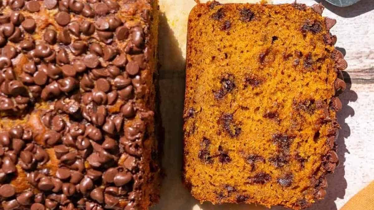 A slice of pumpkin bread with chocolate chips on a cutting board.