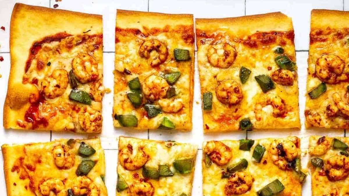 A pizza with shrimp and jalapenos on a white tile.