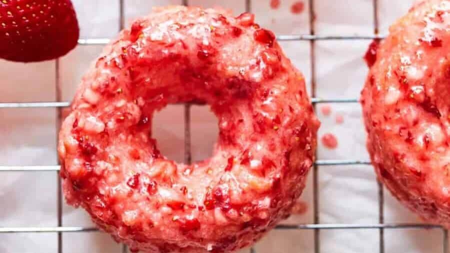 Strawberry glazed donuts on a cooling rack.