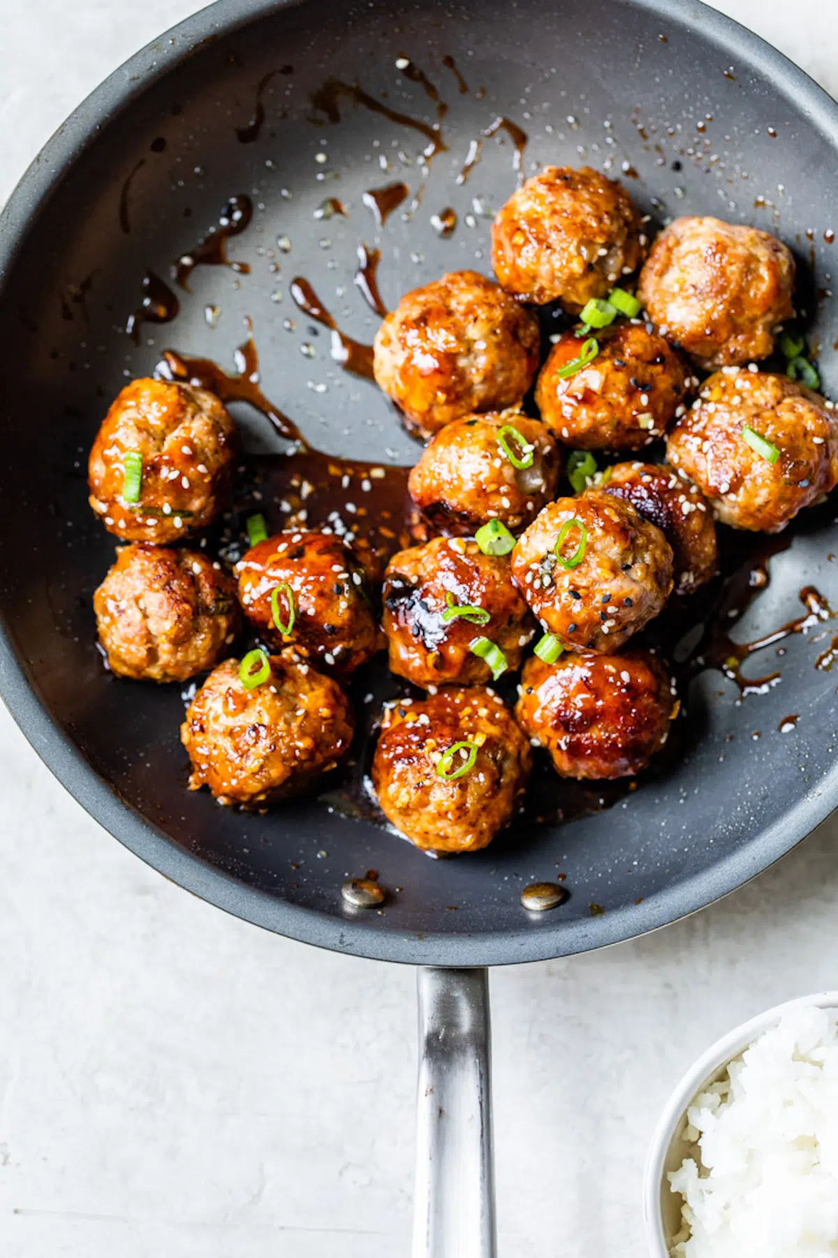 Asian meatballs in a frying pan with rice.