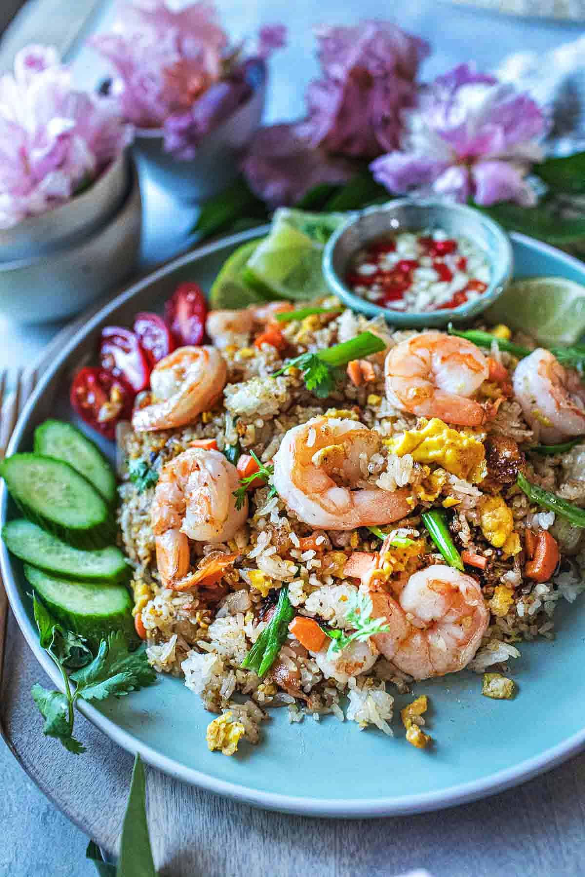 Thai shrimp fried rice on a plate with garnishes. 
