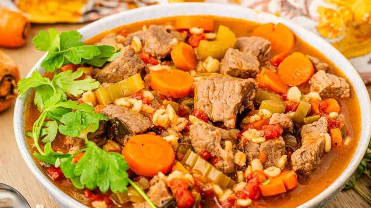 A bowl of beef stew on a wooden table.