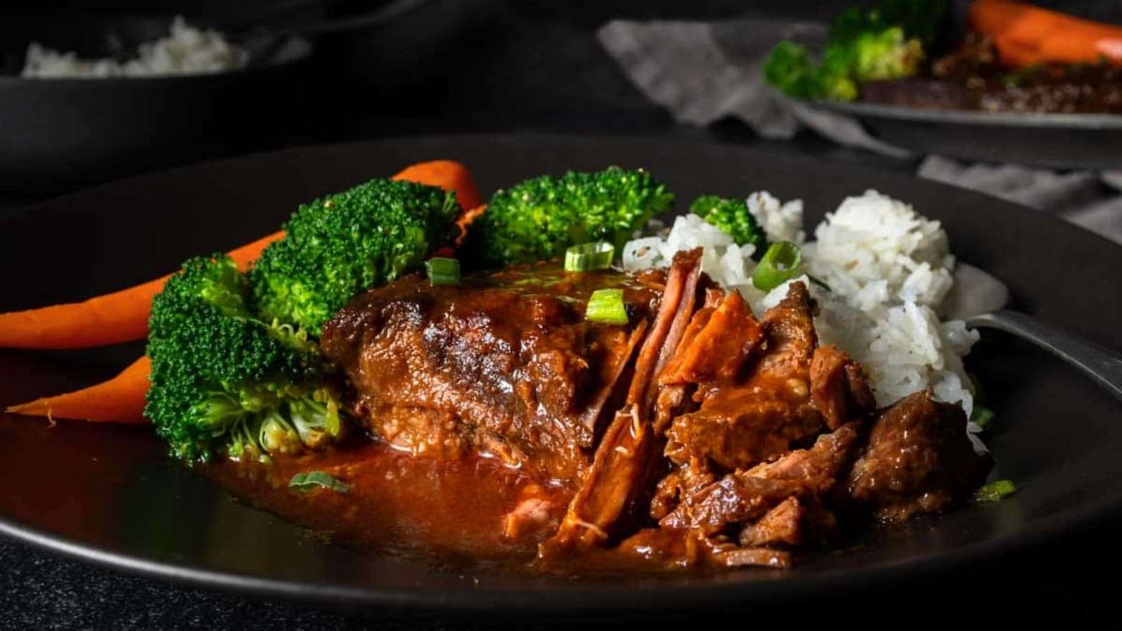 A black plate with beef, broccoli and rice.