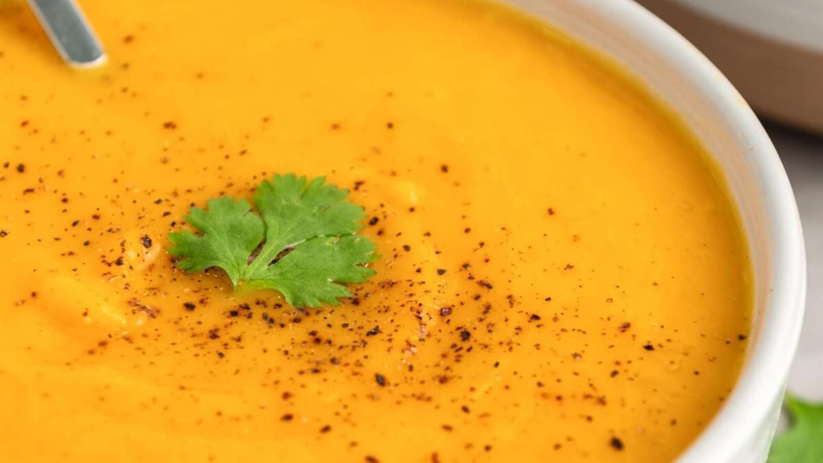 A bowl of carrot soup with a spoon.