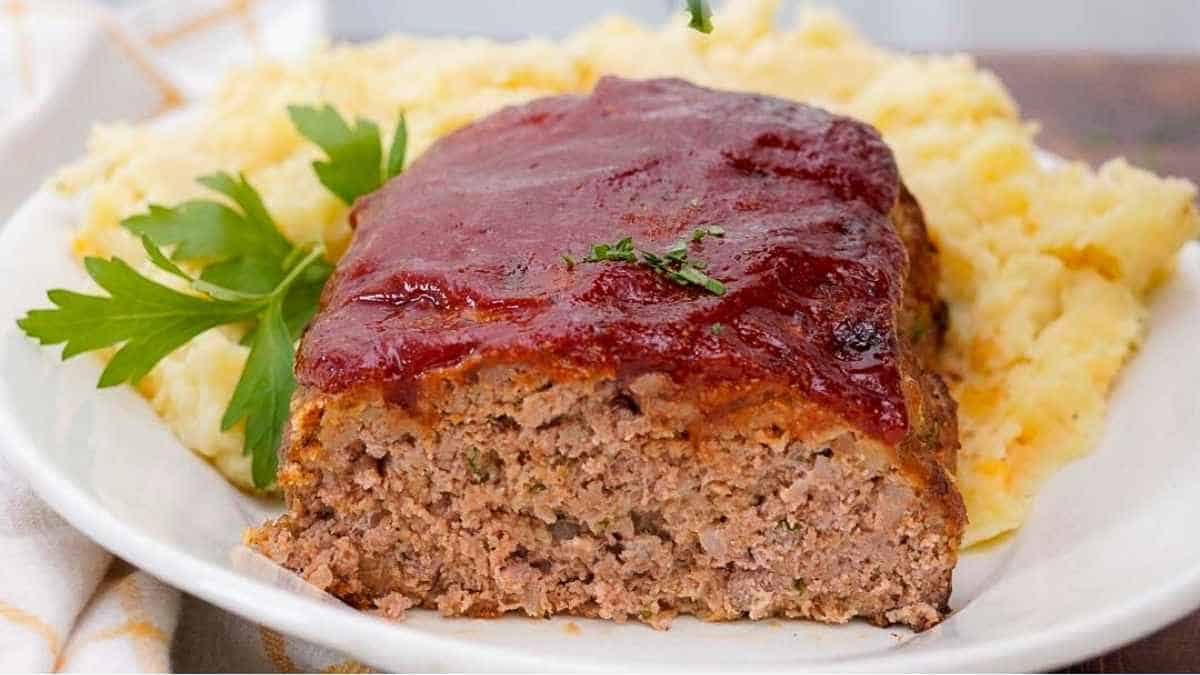 Meatloaf on a plate with mashed potatoes.