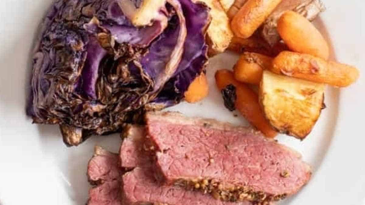 A plate with roast beef, carrots and cabbage.