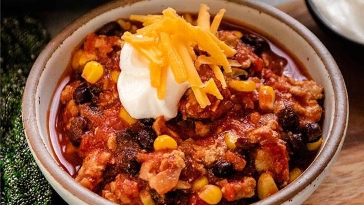Chili in a bowl with sour cream and corn.