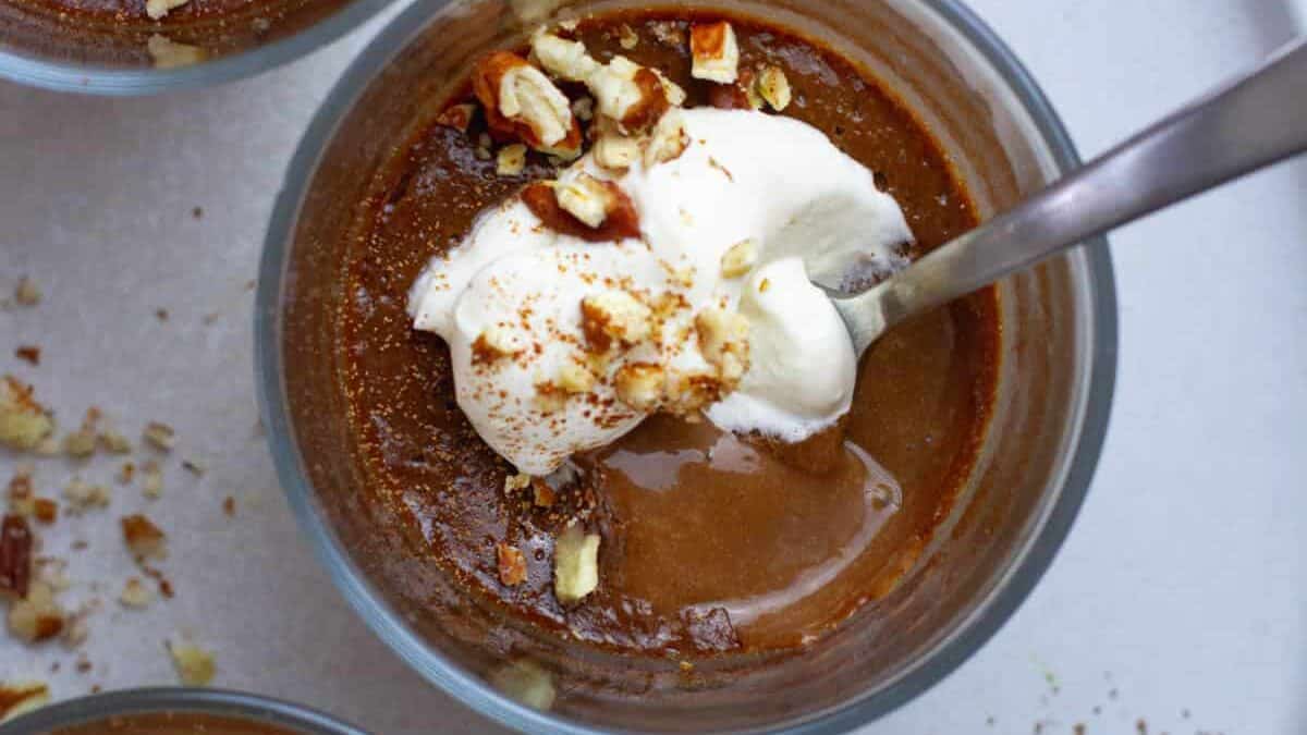 Three bowls of chocolate pudding with whipped cream and nuts.