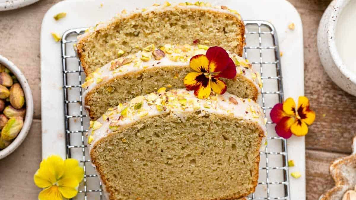 A loaf of bread with pistachios and flowers on a rack.