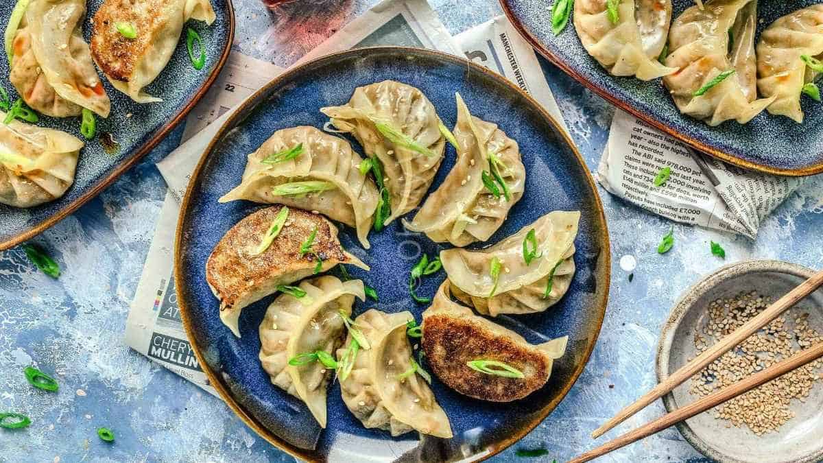 Dumplings on a blue plate with chopsticks.