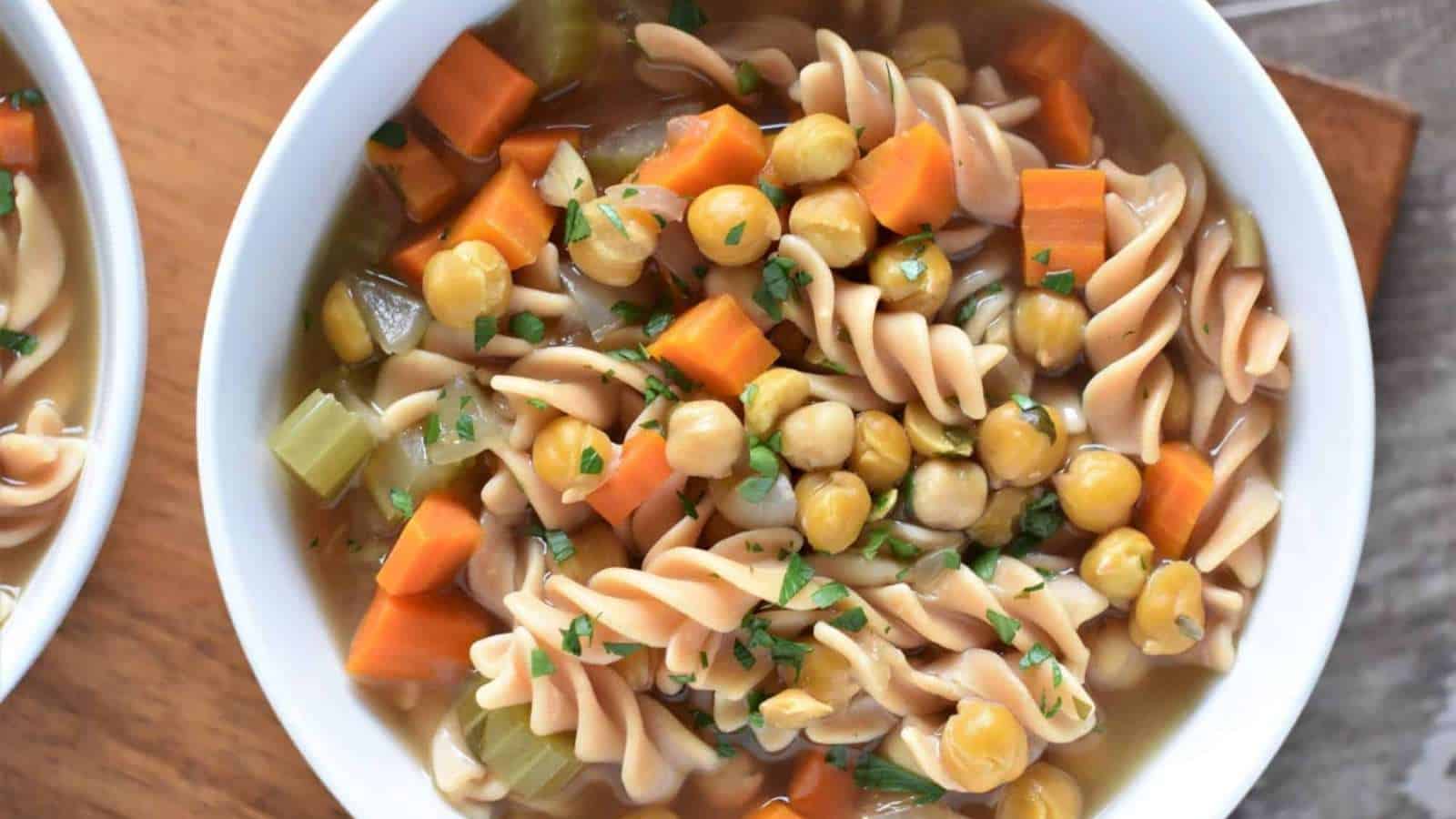 Two bowls of soup with carrots and chickpeas.