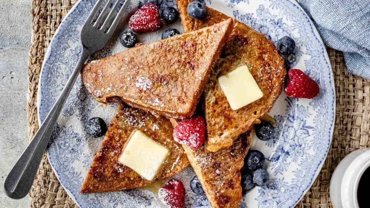 French toast with butter and berries on a plate.