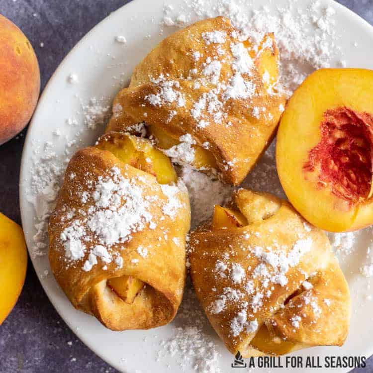 air fryer peaches with powdered sugar on plate close up.
