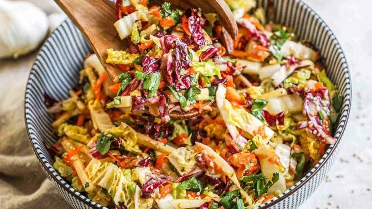 A bowl of asian slaw with a wooden spoon.