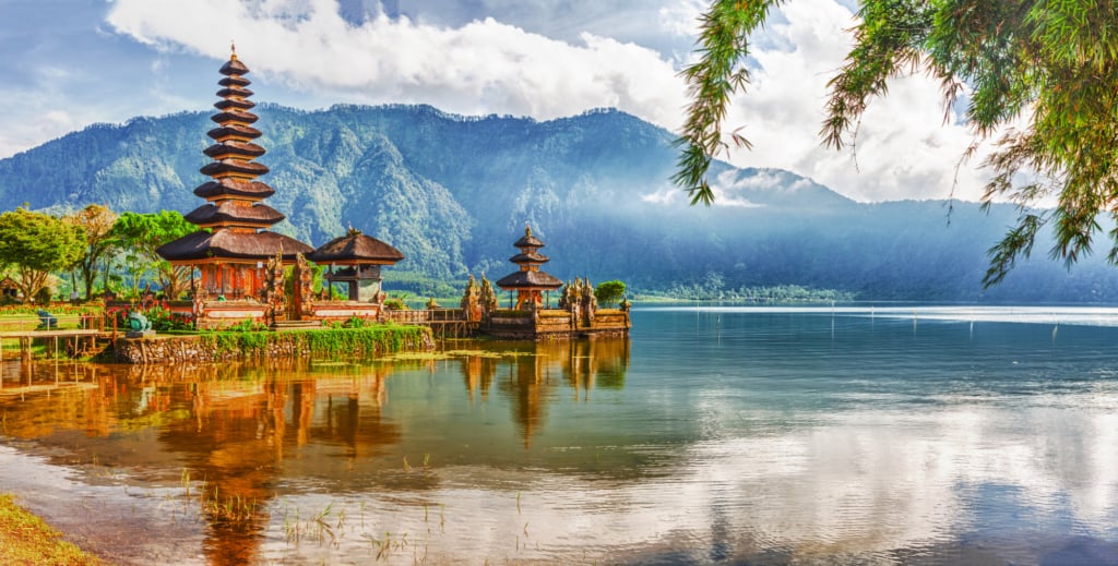 A serene temple in Bali, nestled on the shore of a picturesque lake with majestic mountains as its breathtaking backdrop.