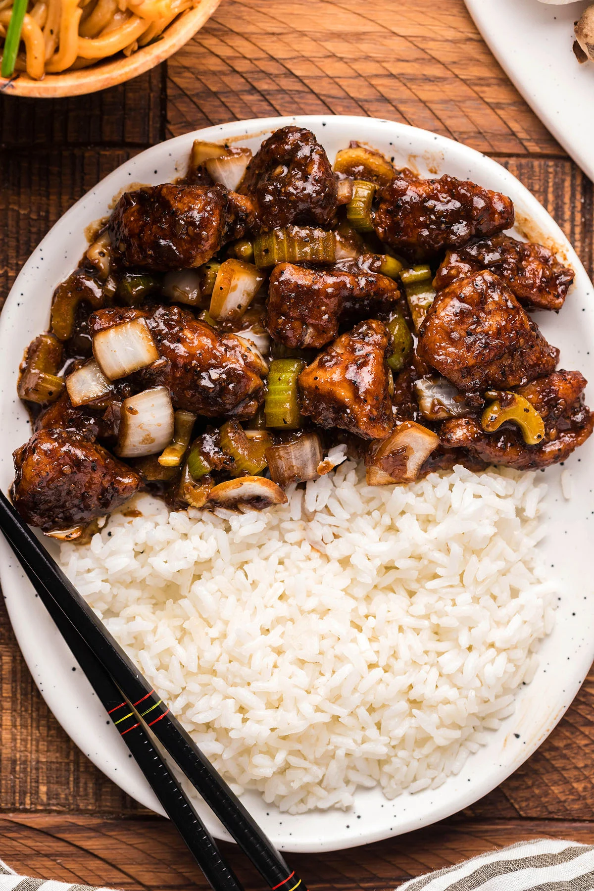A copycat takeout recipe of asian black pepper chicken served with rice and enjoyed using chopsticks. 
