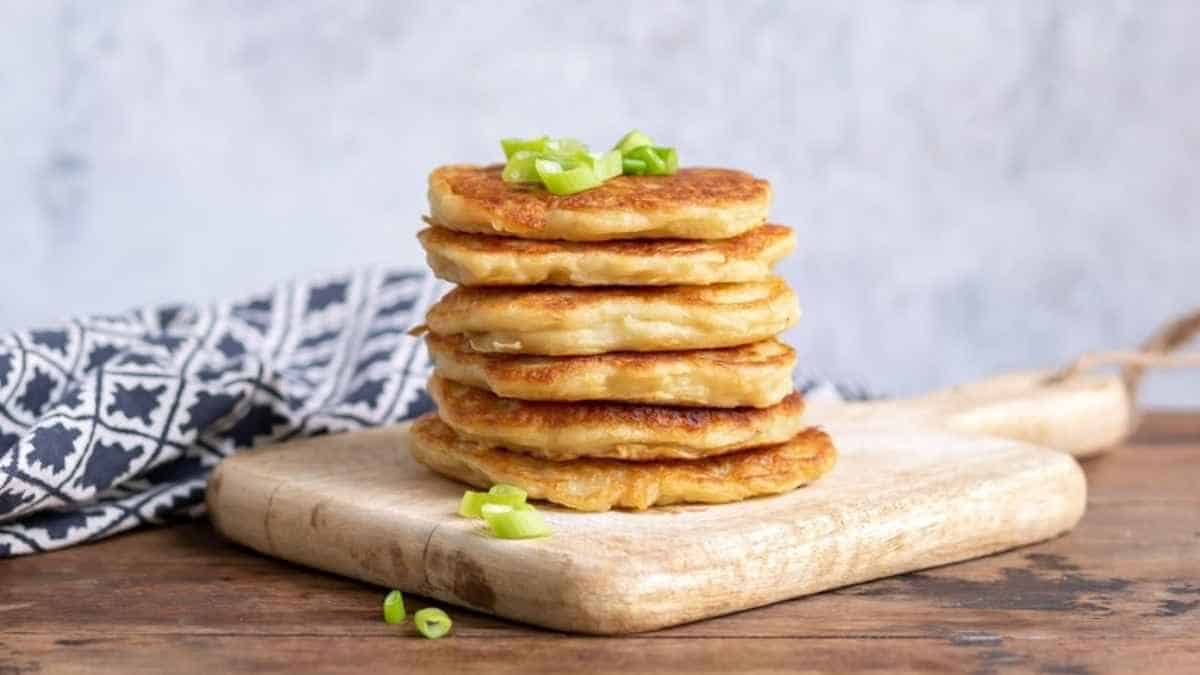 A stack of pancakes on a wooden cutting board.