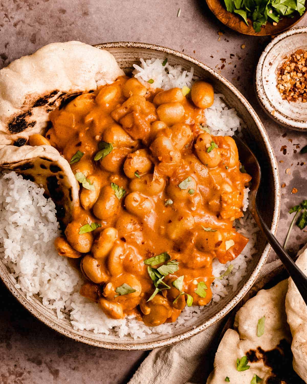 butter bean curry in a bowl on basmati rice and naan. 
