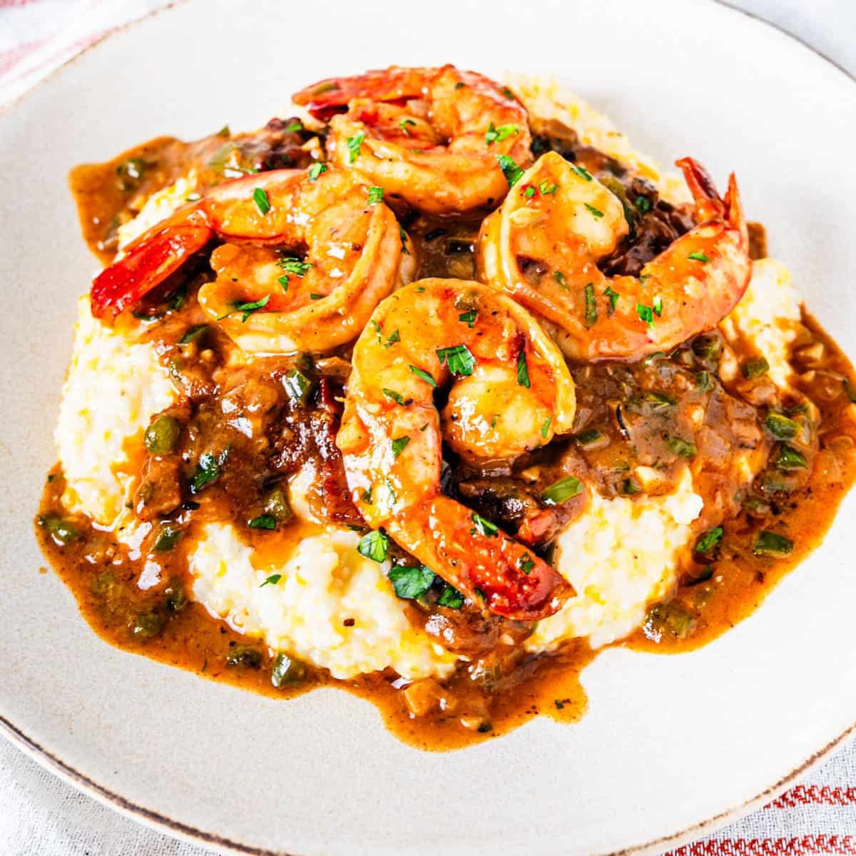 A serving of Cajun shrimp and grits on a plate. 

