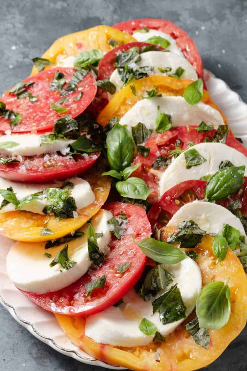 Heirloom tomato caprese salad with mozzarella and basil on a platter. 
