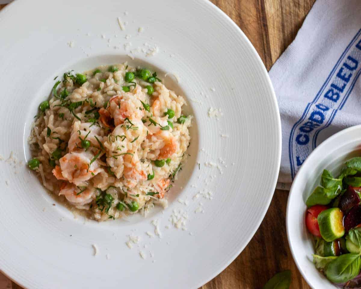 creamy prawn risotto served with a bowl of salad.
