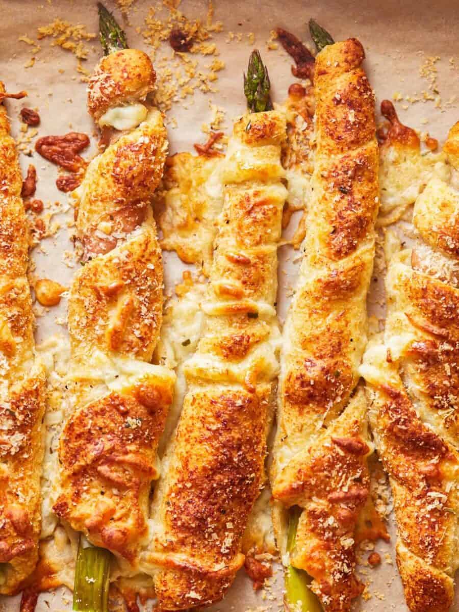 overhead view of asparagus crescent rolls pointing north-south on parchment paper. 

