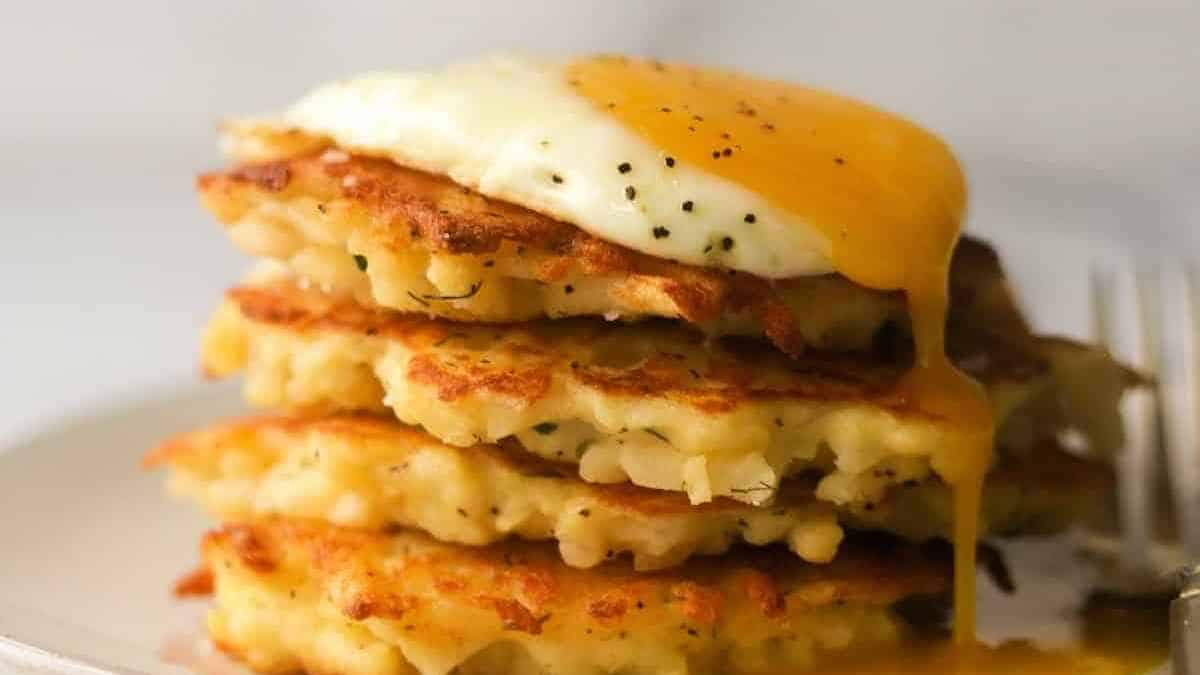 A stack of potato pancakes with an egg on top.