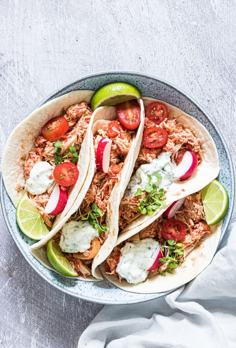 crockpot chicken fajitas served in tortillas with radishes and lime wedges 
