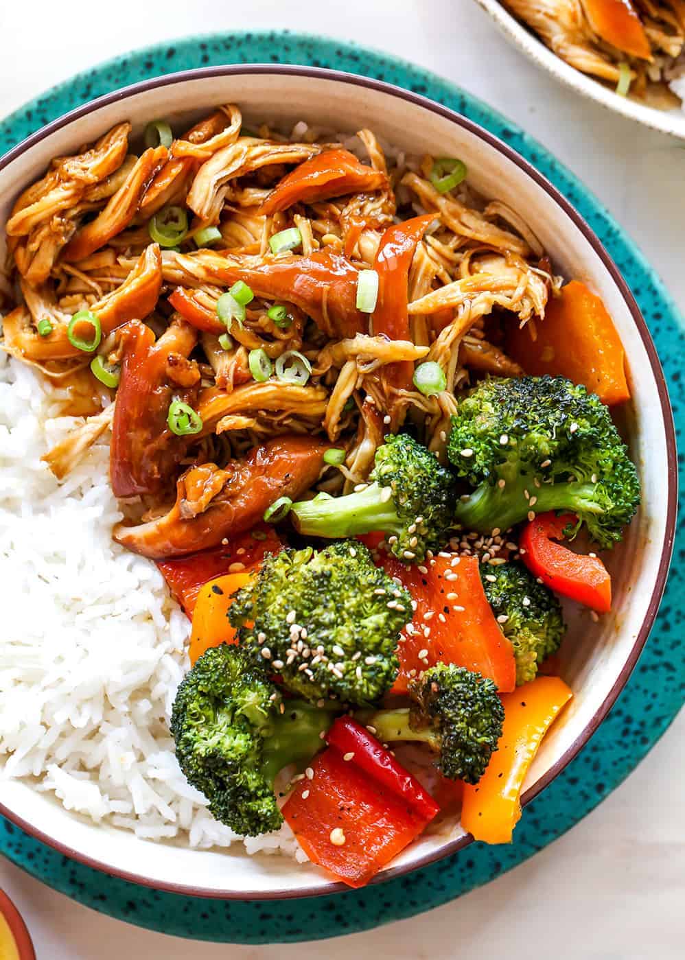 overhead view of a bowl of crockpot teriyaki chicken with veggies and rice / This Crockpot Teriyaki Chicken recipe is an easy recipe perfect for busy weeknights! It only takes 5 minutes to mix together, and then put it in the slow cooker to let it cook. Serve with stir-fried veggies and rice and you have a delicious and healthy meal the whole family will love!
