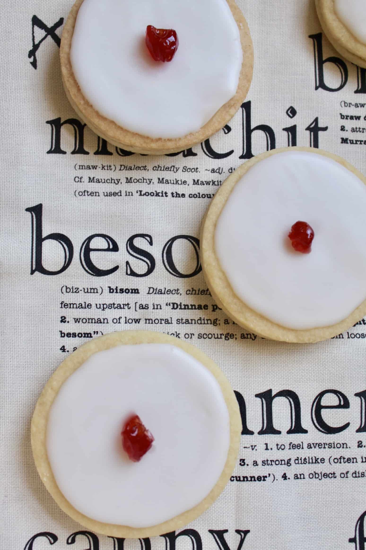 A group of unique cookies with red cherries on top.