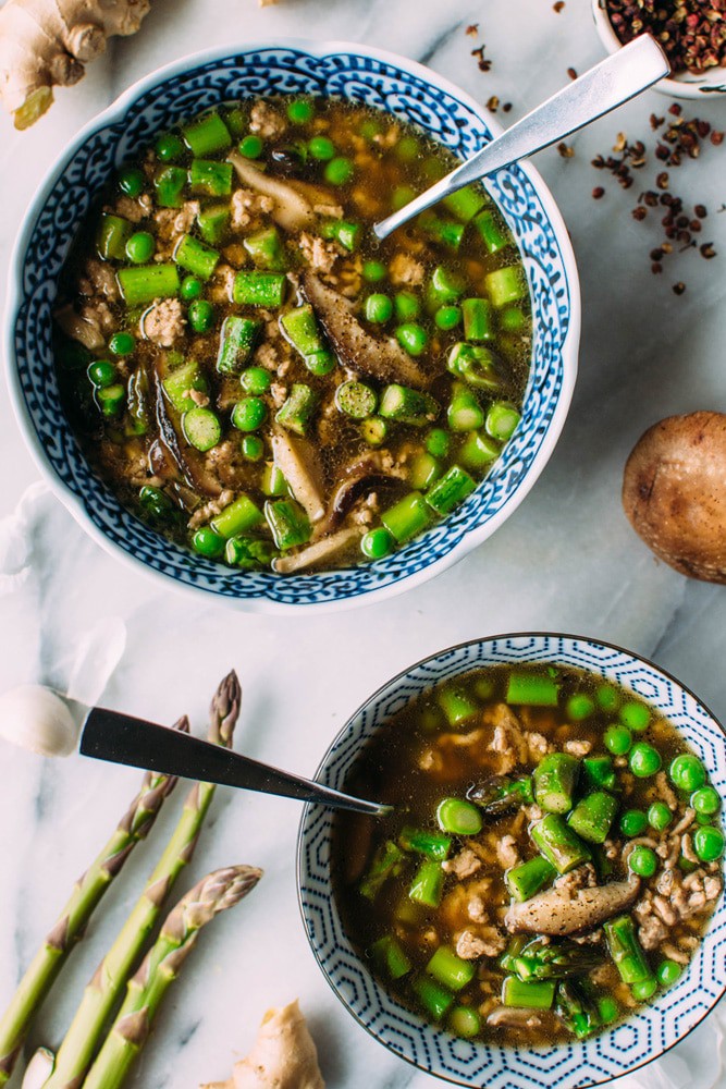 A bowl of soup with peas and mushrooms.